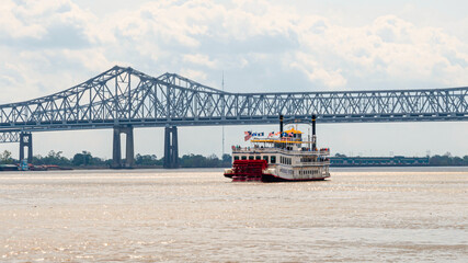 A big cruise ship is traveling at Mississippi River under a cloudy day