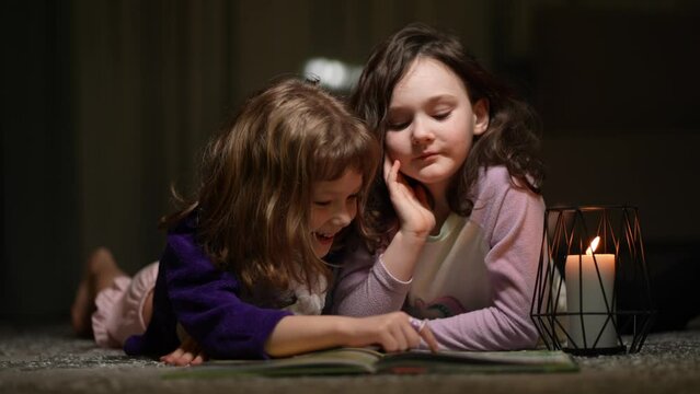 Two little sisters play on the carpet and read fairy tales