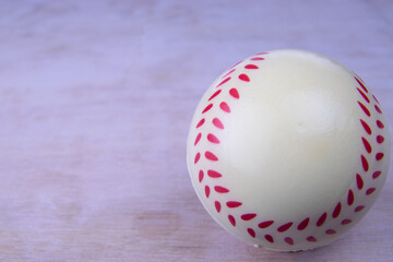 Baseball ball on a white wooden surface wood grain plastic stitches. A toy on a white wooden board. Grain visible. Lots of copy space. Vintage look.