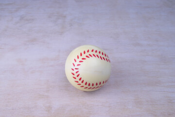 Baseball on a white wooden surface wood grain rubber stitches. A toy on a white wooden board. Grain visible. Lots of copy space. Vintage look.