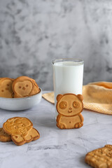 Funny children's cookies in the form of animals and a glass of milk on a gray marble table. Baby food. Baking for children.