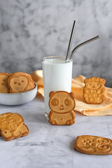 Funny children's cookies in the form of animals and a glass of milk on a gray marble table. Baby food. Baking for children.