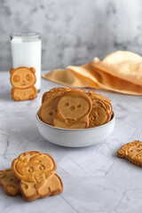 Funny baby cookies in the shape of animals in a gray ceramic bowl on a gray marble table with  a yellow napkin next to it. Baby food. Baking for children.
