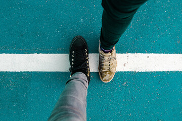 Two people foot standing on a white line on the ground. Border crossing - obrazy, fototapety, plakaty