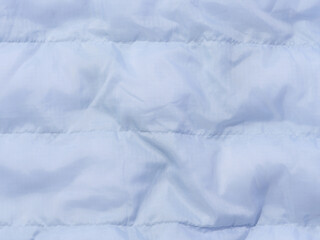 A fragment of blue fabric with down filling and stitching, fabric for jackets and coats