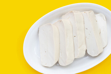 Fototapeta na wymiar White tofu in yellow plate on yellow background