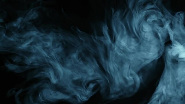 Abstract blue smoke from cigarettes on black background, video close up