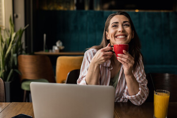 Woman sipping coffee while working on her laptop at a local café