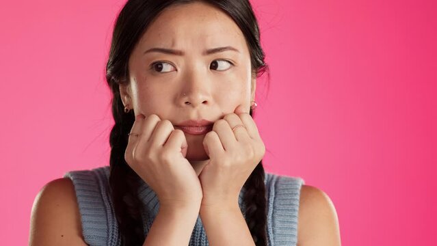 Worried, fear and scared Asian woman with hands on face feeling anxious isolated in a studio pink background. Anxiety, paranoid and female with depression or schizophrenia thinking of crisis