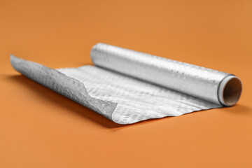 Roll of aluminium foil on orange background