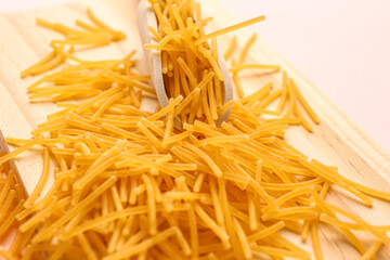 Wooden board with raw vermicelli pasta, closeup