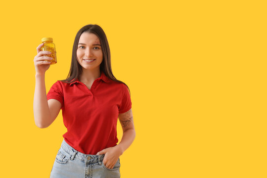 Young Woman With Bottle Of Vitamin Supplements On Yellow Background