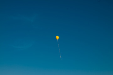 Yellow hot air balloon flies against the blue sky