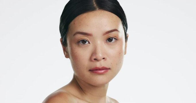 Beauty, skincare and face of an Asian woman in a studio with a natural, cosmetic and health routine. Wellness, self care and portrait of a female model with clear and glowing skin by white background