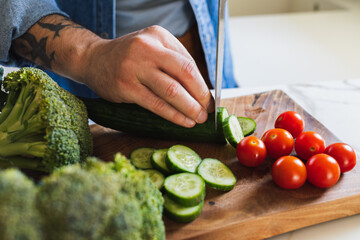 A close-up of a man's hands skillfully preparing a healthy meal with fresh vegetables in his home kitchen.