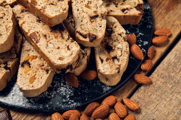 Board with delicious biscotti cookies and almond nuts on wooden background