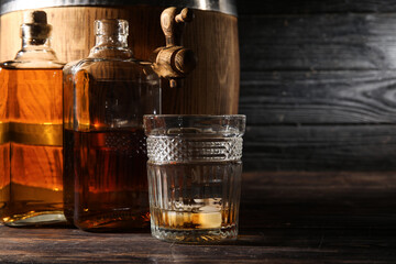Oak barrel with bottles glass of cold whiskey on dark wooden background
