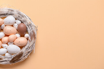 Composition with Easter eggs, wreath and feathers on color background