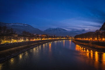 Obraz premium Night view of the city of Trento, Italy with snow capped mountain in background. Night view of a city between mountains and river Adige. Long exposure picture taken in January 2023