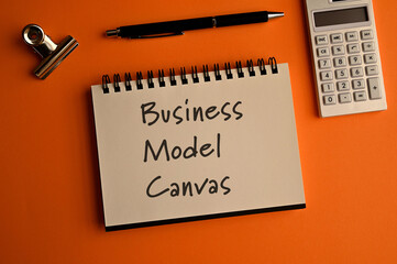 There is a notebook with the word Business Model Canvas. It is eye-catching image.