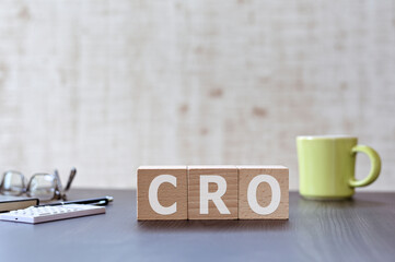 There is wood cube with the word CRO. It is an acronym for Contract Research Organization an eye-catching image.