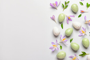 Composition with Easter eggs, crocus flowers and plant leaves on light background