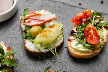 Slate board with tasty sandwiches and sauce, closeup