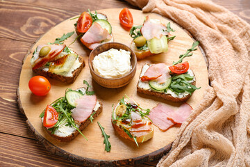 Board with delicious sandwiches and cream cheese on wooden background, closeup