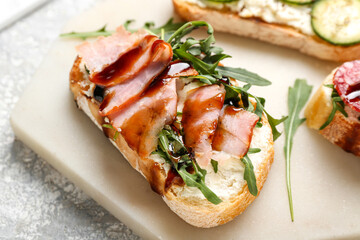 Tasty sandwich with cheese, ham and arugula on board, closeup