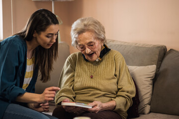 Nurse caretaker helping senior patient woman take her medication from a pill box.