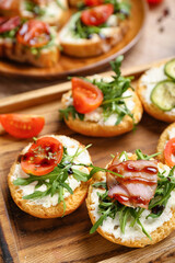 Wooden board with tasty sandwiches, closeup