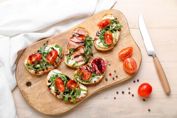 Board with delicious sandwiches on light wooden table