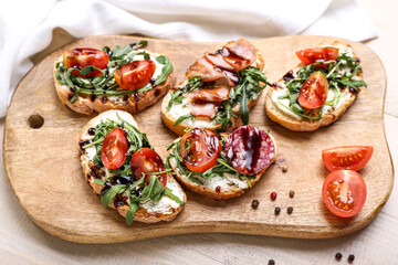 Board with delicious sandwiches on light wooden table, closeup