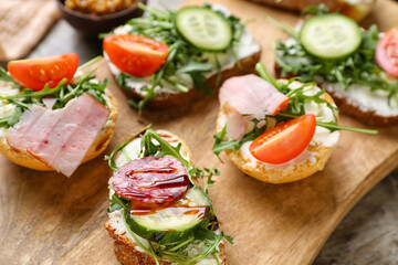 Fototapeta na wymiar Wooden board of delicious sandwiches, closeup