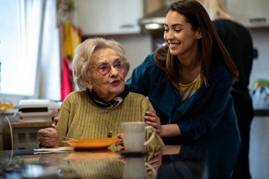 Senior woman and nurse enjoying a nutritious meal together at a dining table in a retirement home.