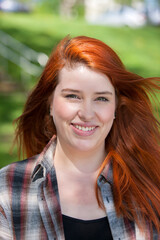 Fototapeta premium Outdoor portrait of young red haired woman.
