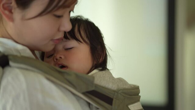 眠る子供を抱く母親