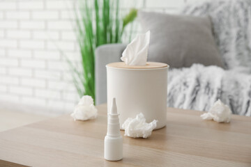 Nasal drops with tissue box on table in living room, closeup. Allergy concept