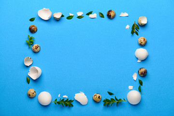 Frame made of Easter eggs and plant leaves on blue background