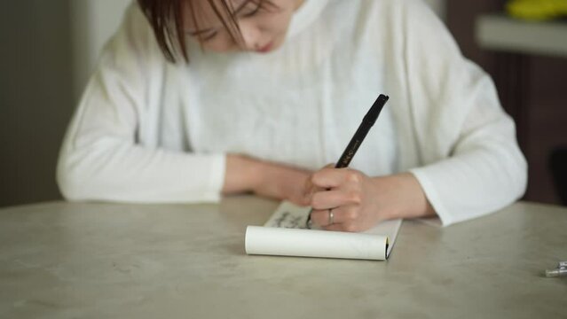 	筆ペンで字を書く女性