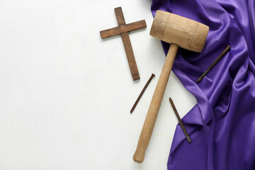 Wooden cross with mallet, nails and purple fabric on white background. Good Friday concept