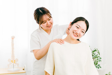 首・頭のマッサージをする整体師の女性と患者（ストレートネック・首こり・鞭打ち）
