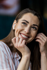 Fototapeta premium A portrait of a woman wearing wireless headphones, smiling and looking happy