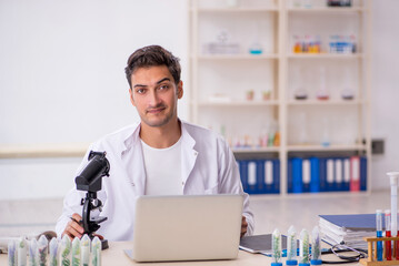 Young male chemist in drugs synthesis concept