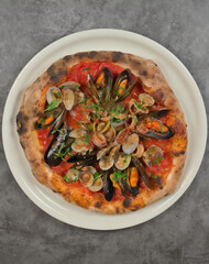 Authentic and delicious seafood pizza, mussels, clams, prawns on a gray marbled background, copyspace