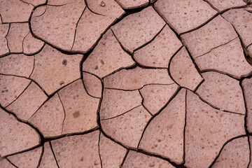 Close up of dried brown mud with cracks and wet raindrops on the surface.  