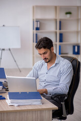 Young male employee and too much work in the office