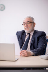 Old male employee working in the office