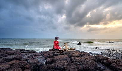 A woman sitting on a rock watching the sunrise in  