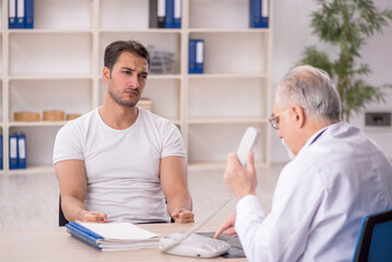 Obraz premium Young male patient visiting old male doctor